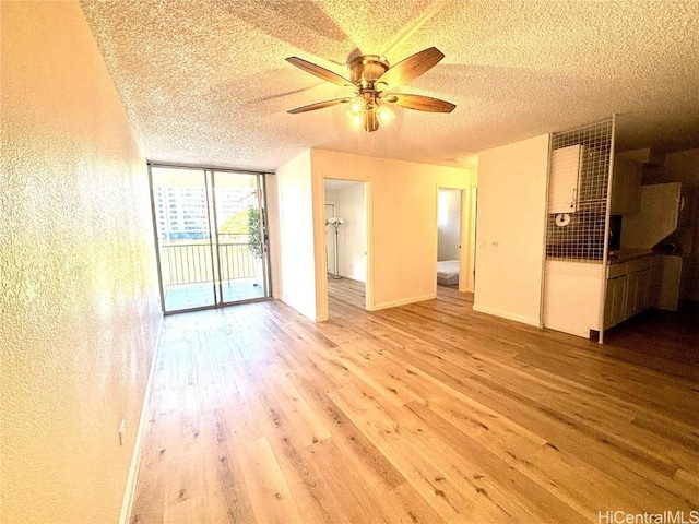 unfurnished living room with ceiling fan, floor to ceiling windows, a textured ceiling, and light hardwood / wood-style flooring