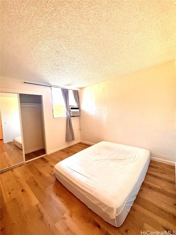 unfurnished bedroom featuring a closet, wood-type flooring, and a textured ceiling