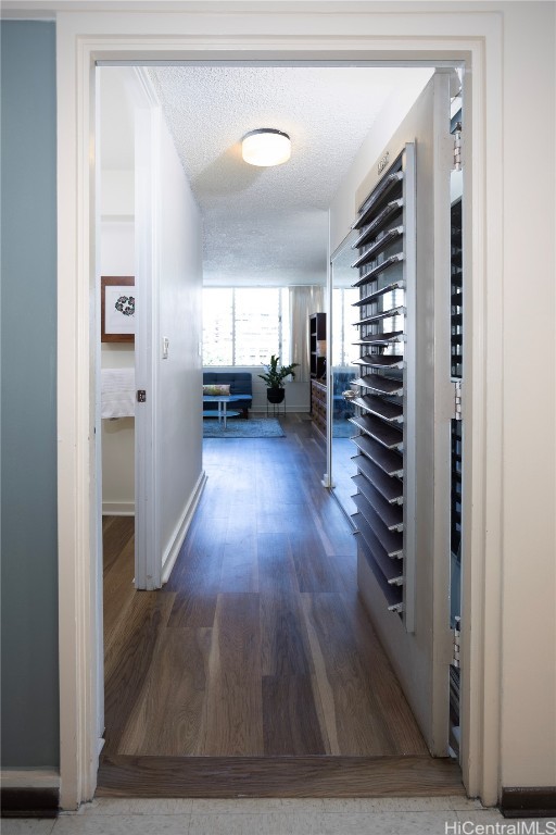 corridor with a textured ceiling and dark hardwood / wood-style floors