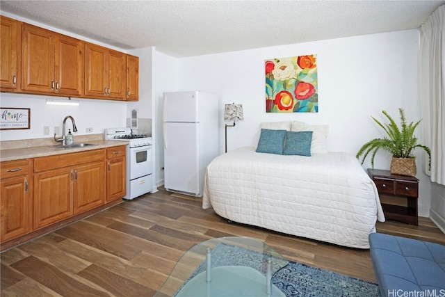 kitchen with white appliances, a textured ceiling, dark hardwood / wood-style flooring, and sink