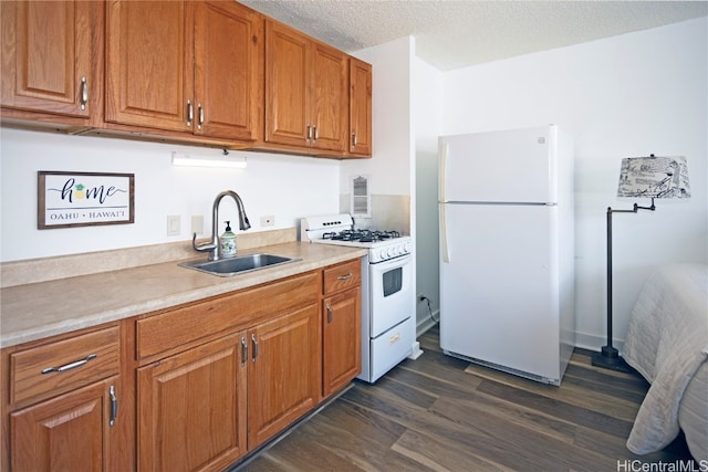 kitchen featuring sink, a textured ceiling, dark hardwood / wood-style floors, and white appliances