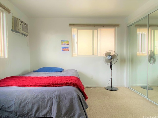 carpeted bedroom with baseboards, a wall mounted AC, and a closet