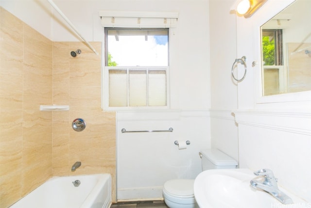 full bathroom featuring toilet, tiled shower / bath combo, sink, and a wealth of natural light