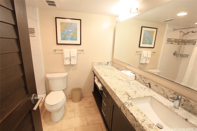 bathroom with vanity, tile patterned flooring, toilet, and tiled shower