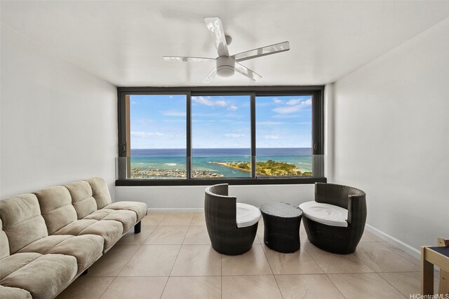 tiled living room with expansive windows, a water view, and ceiling fan