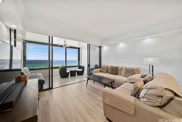 living room with crown molding, light hardwood / wood-style flooring, a water view, and ceiling fan