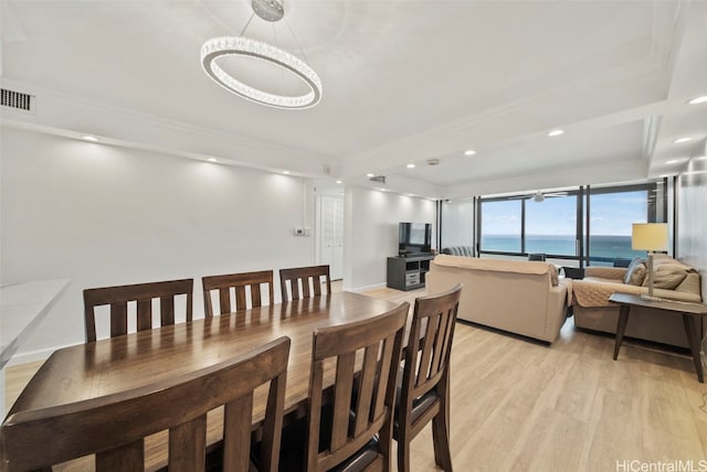 dining room featuring a notable chandelier, ornamental molding, and light wood-type flooring