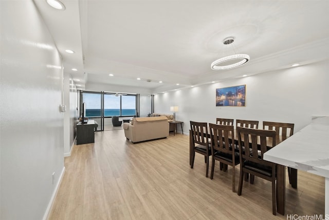 dining room with a chandelier, light hardwood / wood-style flooring, and a water view