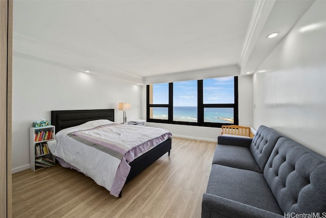 bedroom featuring radiator heating unit, crown molding, a water view, and wood-type flooring