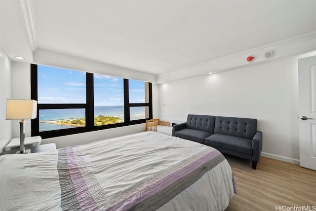 bedroom with ornamental molding, light hardwood / wood-style flooring, and a water view