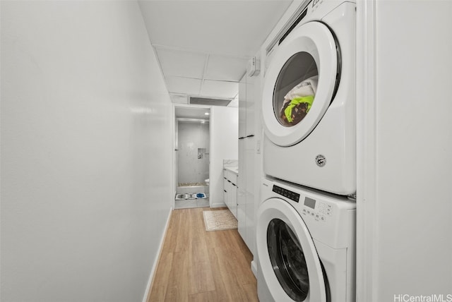 washroom featuring stacked washer / dryer and light hardwood / wood-style flooring