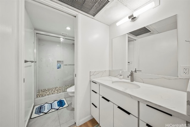 bathroom featuring toilet, tile patterned flooring, vanity, and a shower with door