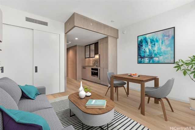 living room featuring sink and light hardwood / wood-style flooring