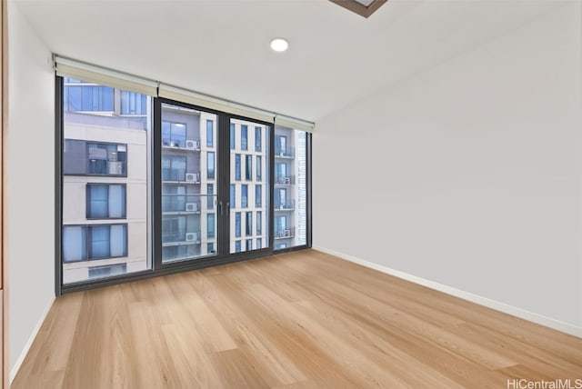 spare room featuring a wall of windows and light hardwood / wood-style floors