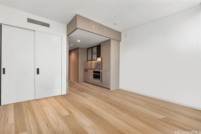 unfurnished living room featuring sink and light hardwood / wood-style floors