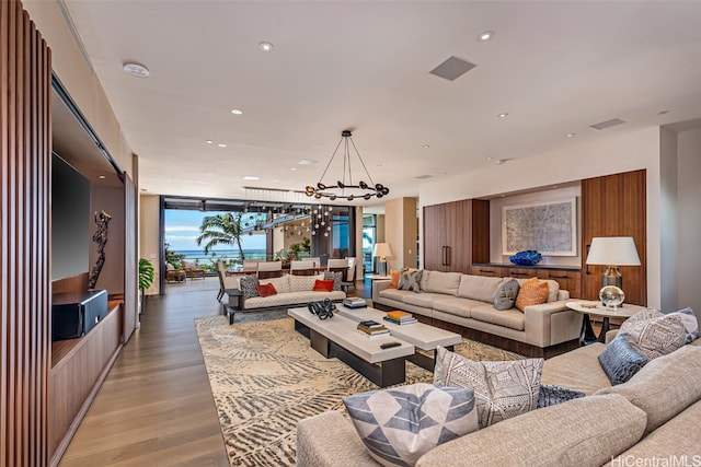 living room with a wall of windows, light hardwood / wood-style flooring, and a chandelier