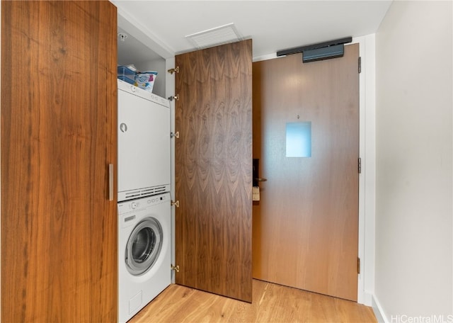 washroom with stacked washer / drying machine and light wood-type flooring