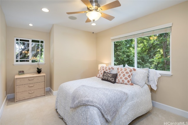 bedroom with light carpet, multiple windows, and ceiling fan