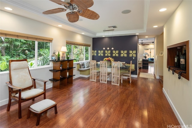 interior space with ornamental molding, a tray ceiling, dark wood-type flooring, and ceiling fan