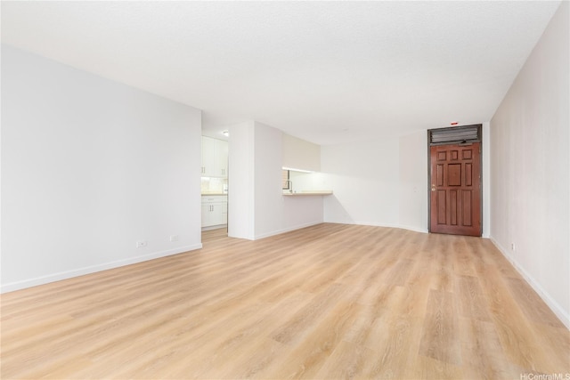 unfurnished living room with baseboards and light wood-type flooring