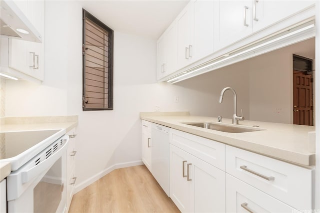 kitchen featuring white cabinets, under cabinet range hood, white appliances, a sink, and light wood-style floors