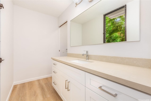 bathroom with baseboards, wood finished floors, and vanity