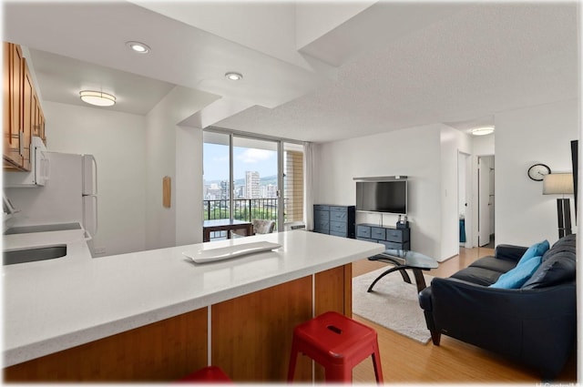 2345 Ala Wai Blvd Unit 1814, Honolulu, HI 96815 - kitchen with open floor plan, a peninsula, light wood-style flooring, brown cabinets, and recessed lighting