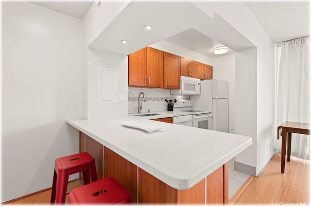 kitchen featuring white appliances, kitchen peninsula, sink, and light wood-type flooring