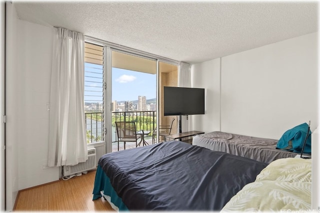 bedroom with a textured ceiling, light wood-type flooring, and floor to ceiling windows