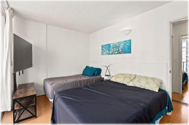 bedroom with light hardwood / wood-style flooring and a textured ceiling