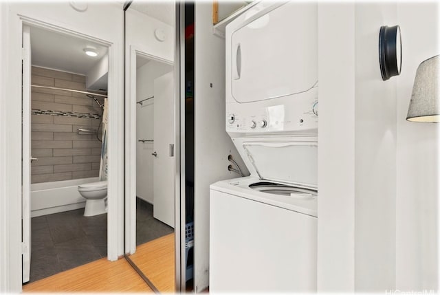 laundry room featuring tile patterned floors and stacked washer / dryer