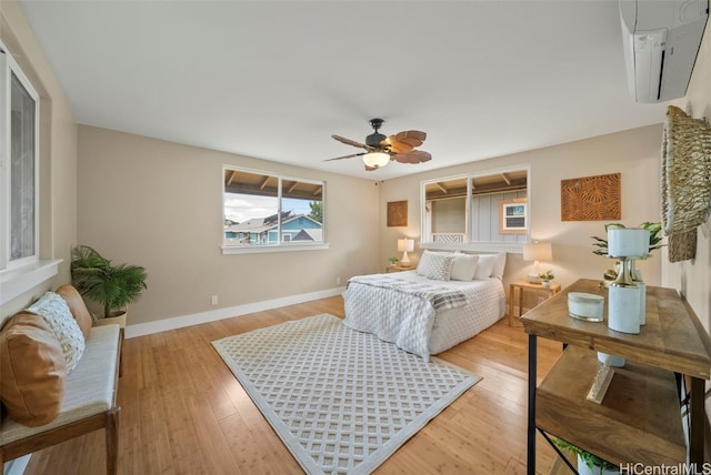 bedroom featuring a wall mounted AC, ceiling fan, and light hardwood / wood-style floors