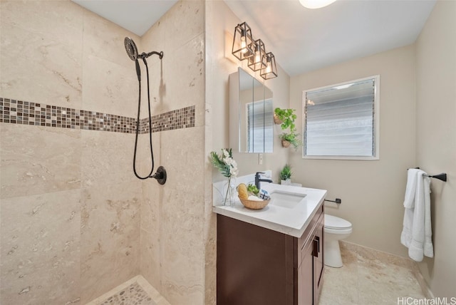 bathroom featuring a tile shower, vanity, and toilet