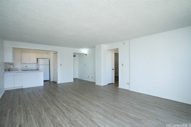 unfurnished living room with a textured ceiling, hardwood / wood-style flooring, and sink