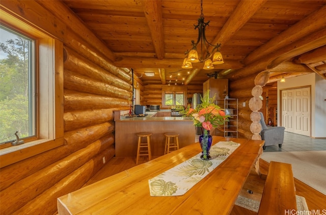 dining room with log walls, beamed ceiling, and a healthy amount of sunlight