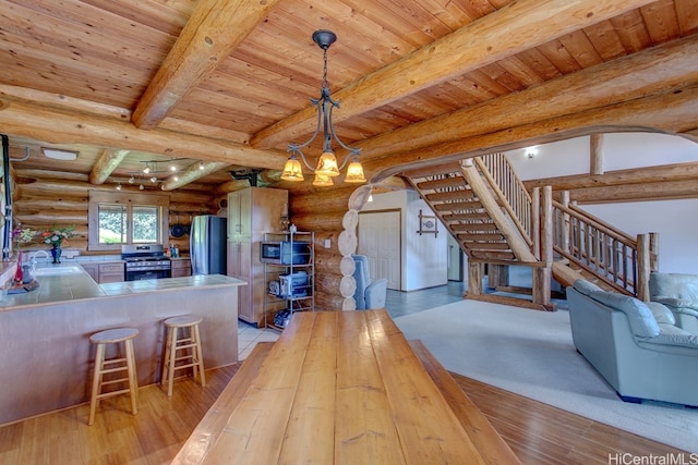 kitchen with beamed ceiling, light hardwood / wood-style flooring, wood ceiling, and rustic walls