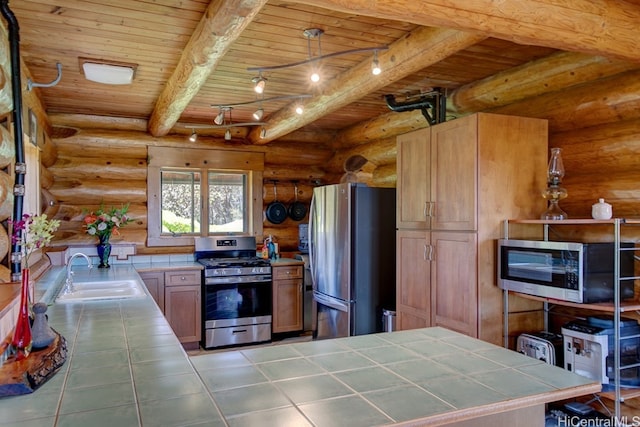 kitchen featuring beam ceiling, appliances with stainless steel finishes, sink, tile counters, and decorative light fixtures