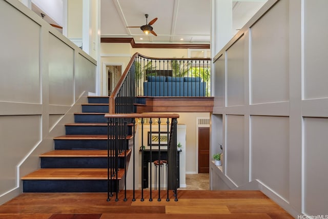 stairway with wood finished floors and ceiling fan