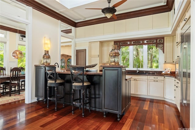 interior space with ceiling fan, dark countertops, dark wood-type flooring, and a breakfast bar area