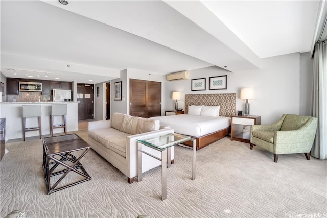 bedroom featuring a wall mounted air conditioner, light colored carpet, and stainless steel refrigerator