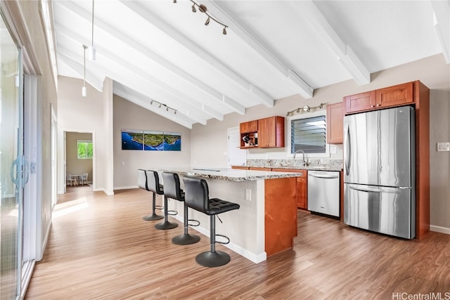 kitchen featuring light hardwood / wood-style flooring, lofted ceiling with beams, appliances with stainless steel finishes, and a center island