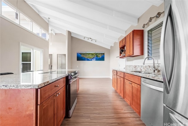 kitchen with hardwood / wood-style flooring, stainless steel appliances, sink, a center island, and light stone counters