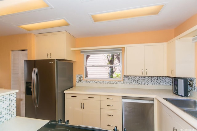 kitchen featuring tasteful backsplash, appliances with stainless steel finishes, light countertops, and a sink
