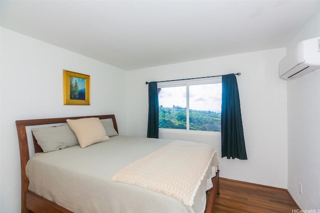 bedroom with an AC wall unit and wood finished floors
