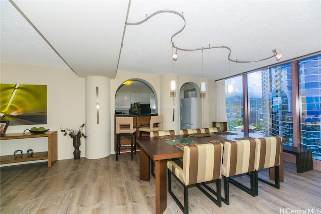 dining space featuring a textured ceiling, wood-type flooring, and expansive windows