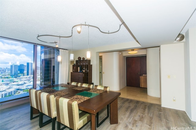 dining area featuring expansive windows, wood-type flooring, and a textured ceiling