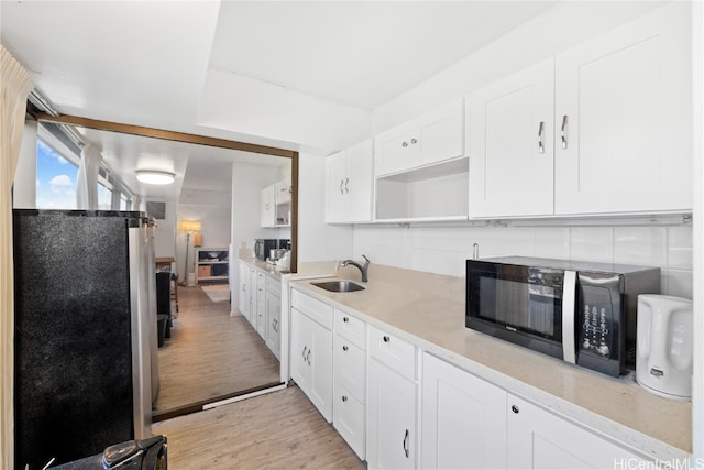 kitchen featuring tasteful backsplash, sink, stainless steel fridge, white cabinets, and light hardwood / wood-style flooring