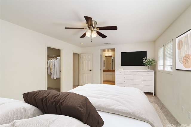 bedroom featuring light colored carpet, ceiling fan, a spacious closet, connected bathroom, and a closet