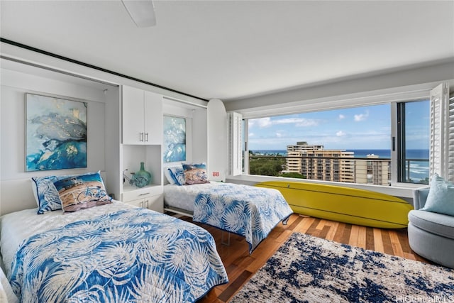 bedroom with a water view and hardwood / wood-style flooring