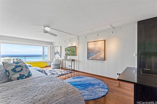 bedroom featuring wood-type flooring, a water view, and ceiling fan